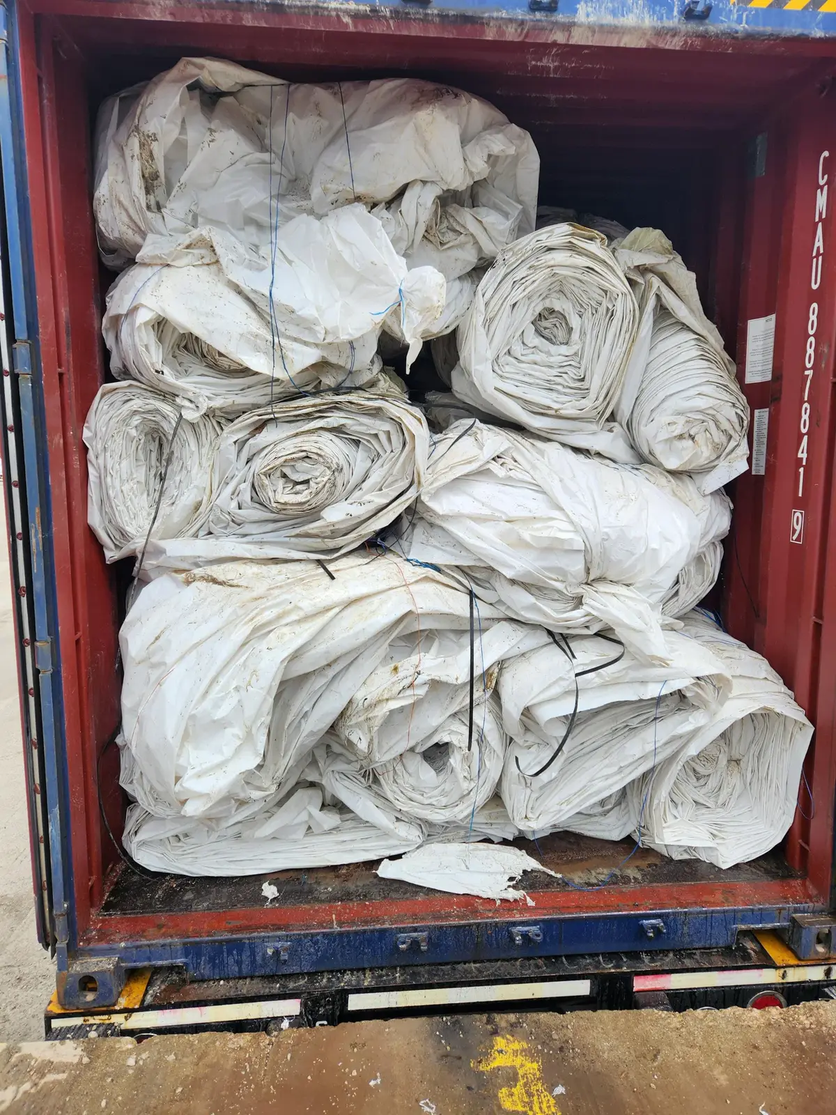 Used white greenhouse film rolls loaded inside a shipping container